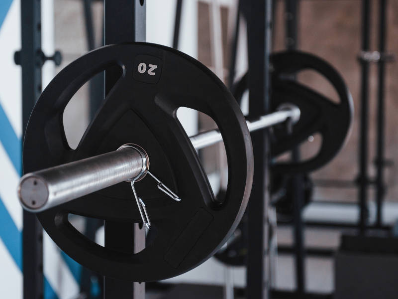 A barbell loaded with a 20 kilograms plate on each side in a squat rack.