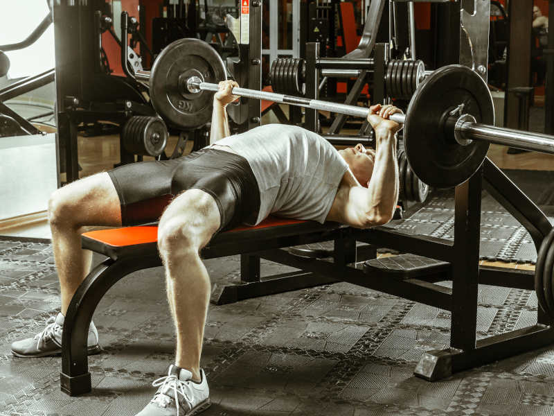 A man bench pressing in a gym.