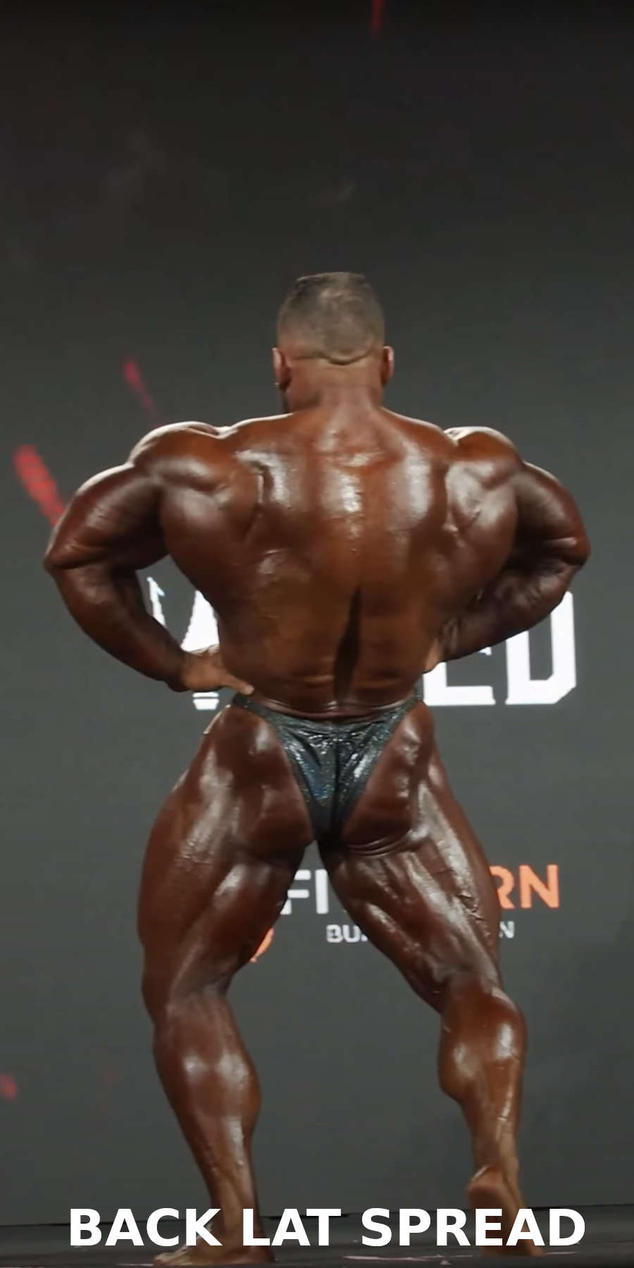 A bodybuilder performing the back lat spread pose on stage during a bodybuilding competition 
