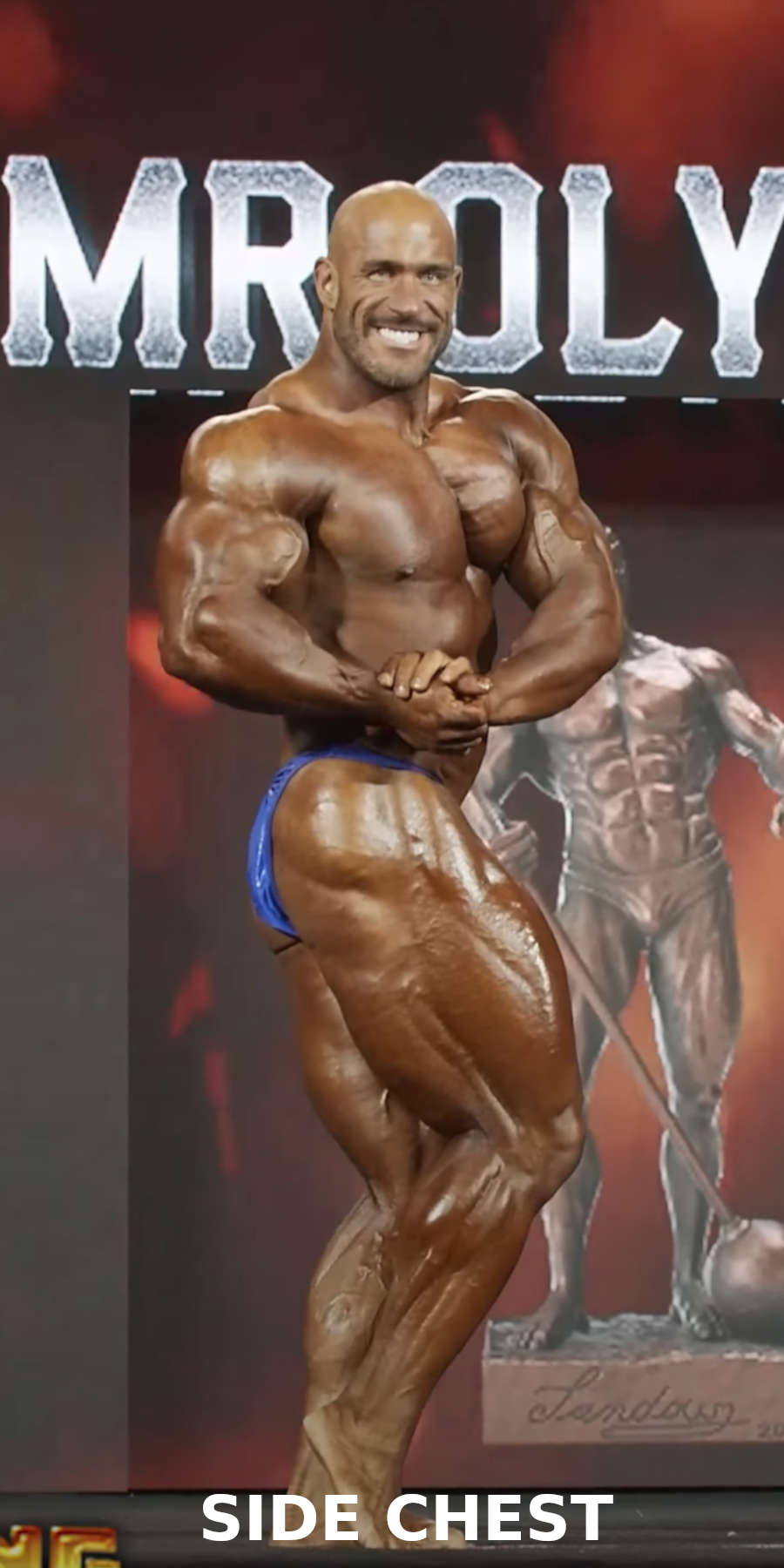 A bodybuilder performing the side chest pose on stage during a bodybuilding competition 
