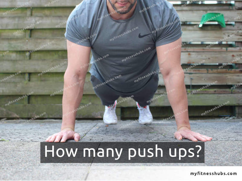 Front view of a fit man in workout clothing outdoors in the top position of a push up.