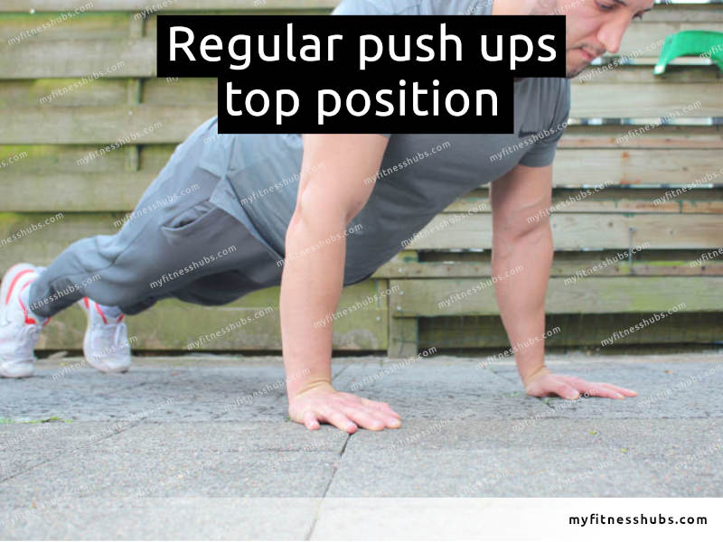 A view of a front angle of an athletic man in the top position of a push up done outdoors.
