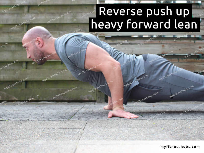 A side view of an athletic man in a reverse grip push up on the ground outdoor with heavy forward leaning of his upper body.