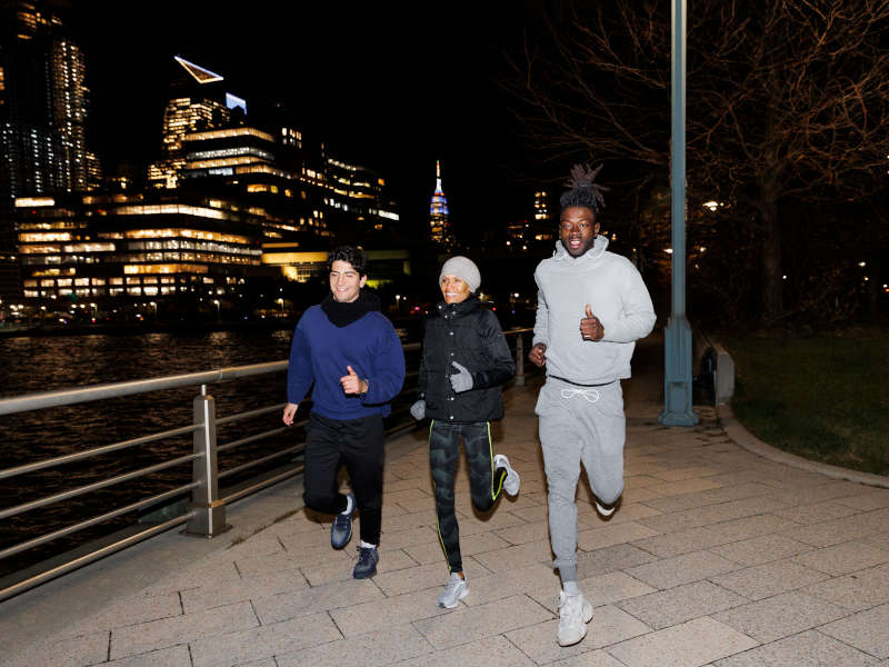 Three persons working out at night by going for a run outside in the city.
